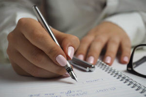 Frau schreibt mit Füller auf Schreibblock